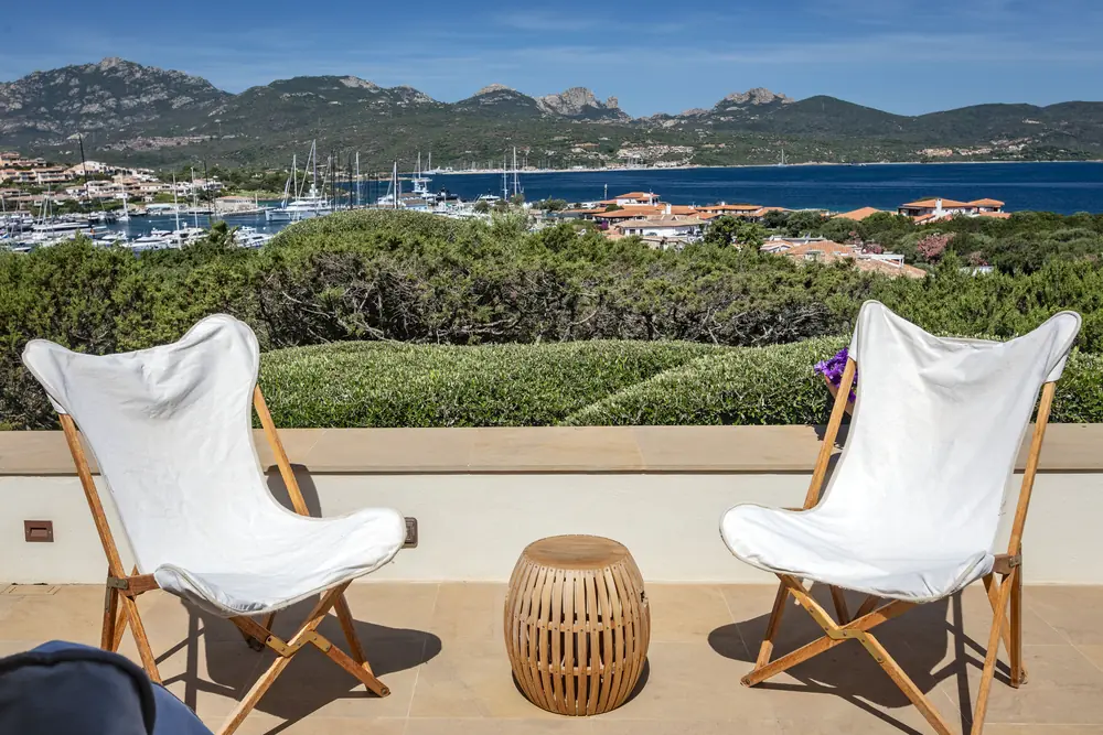 Poltrone bianche sulla terrazza con vista sul porto di Porto Rotondo